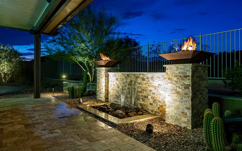Custom stacked-stone water feature with fire bowls