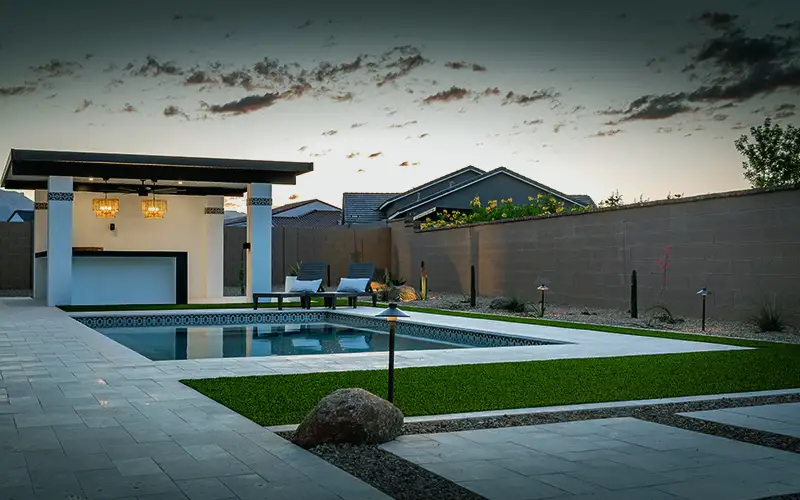 Backyard pool and covered cabana with artificial turf
