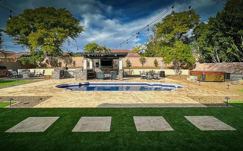 Backyard pool and pergola bar with string lighting at dusk