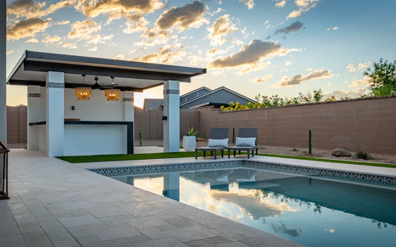 Custom in-ground pool with covered pergola bar at dusk
